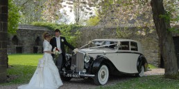 Newlyweds posing with a wedding car in Yorkshire