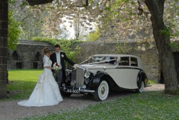 Newlyweds posing with a wedding car in Yorkshire